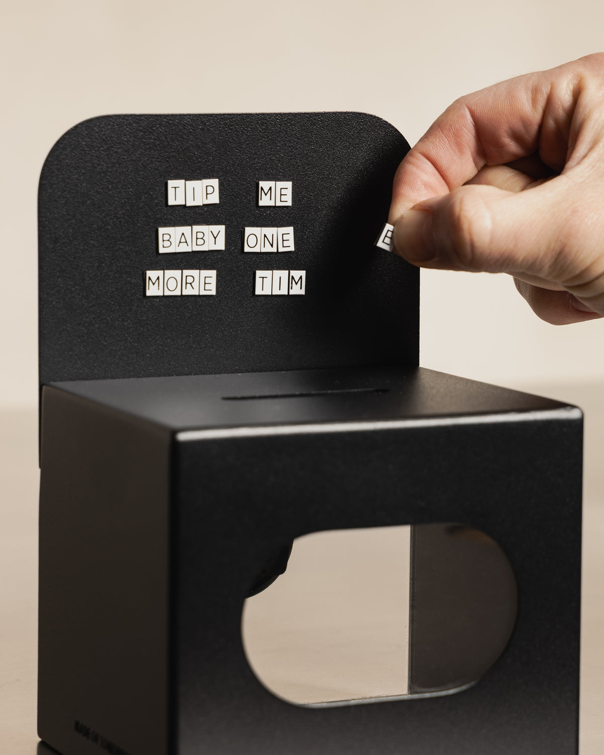 Hand arranging MOT magnetic letters on the black FOLD Tip Box header