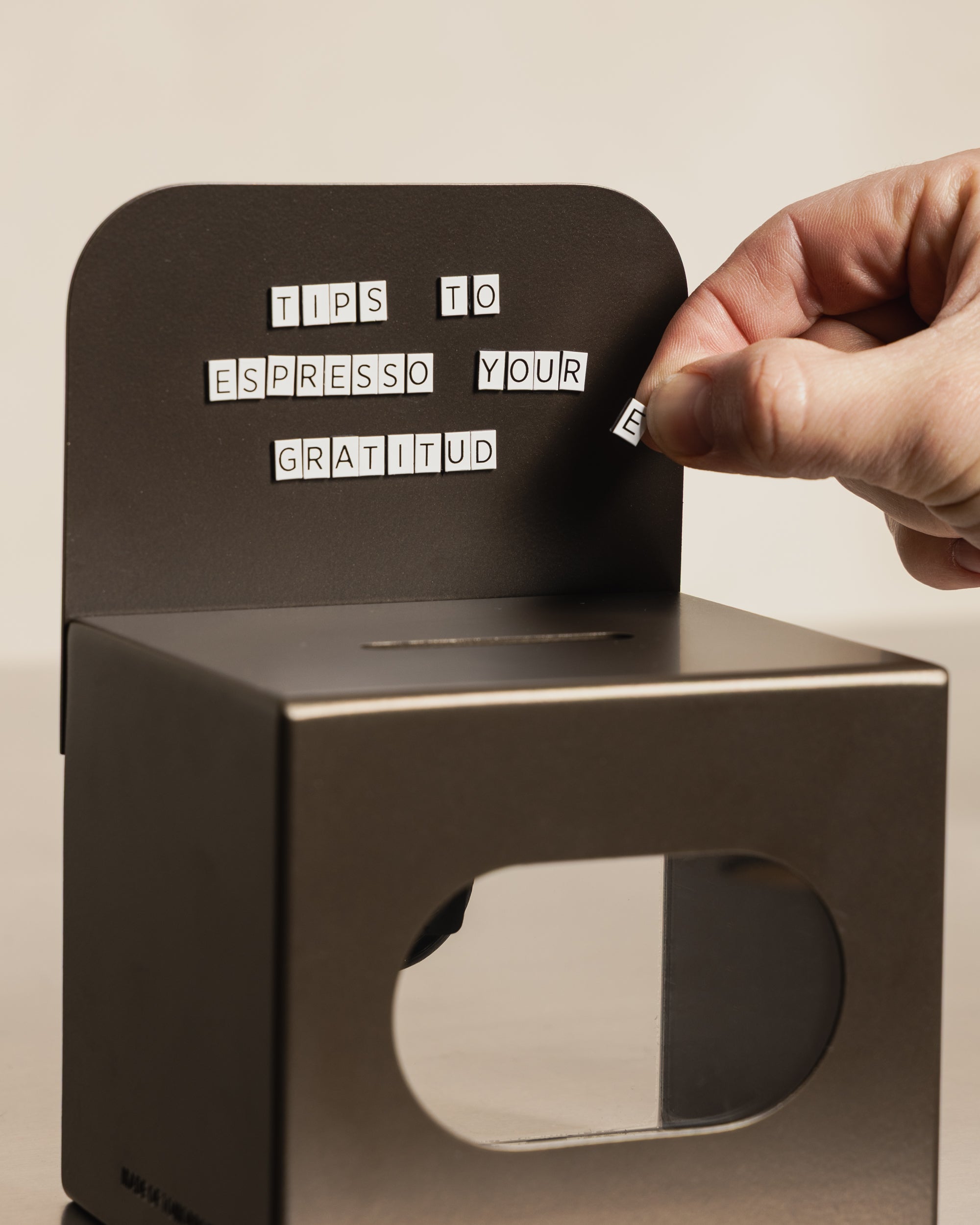 Hand arranging MOT magnetic letters on the bronze FOLD Tip Box header