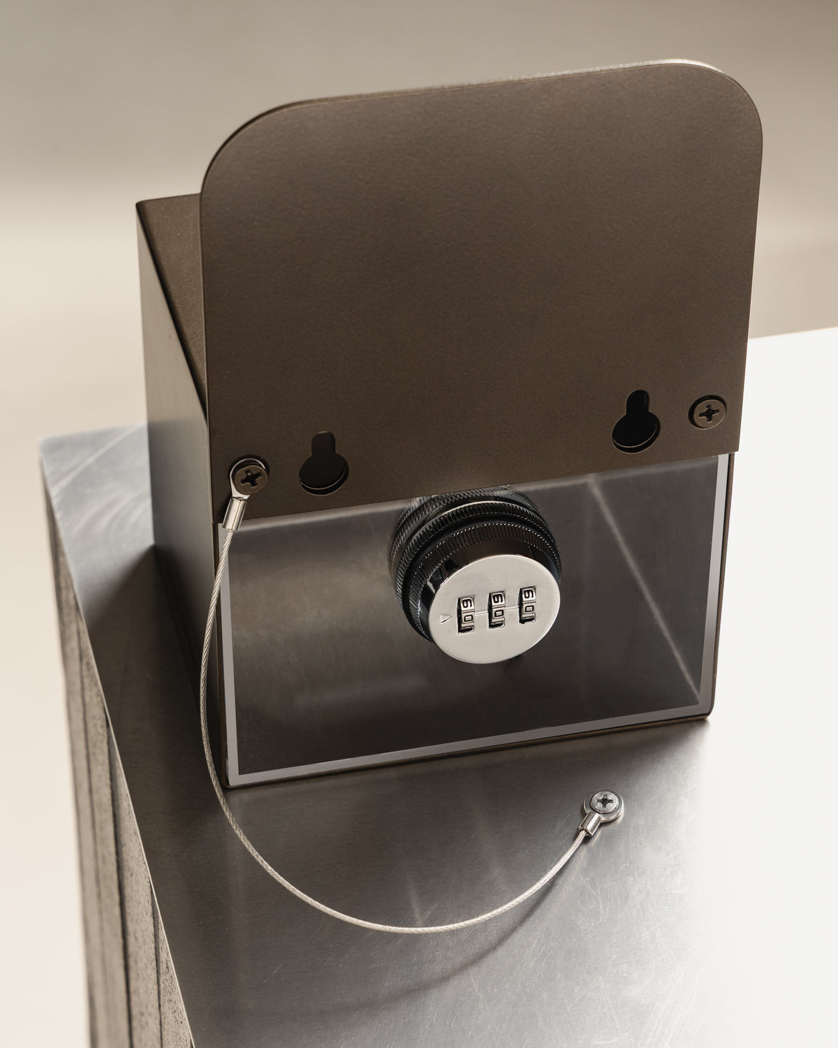 Rear view of the bronze FOLD Tip Box showing the combination lock, security chain and keyhole fixings