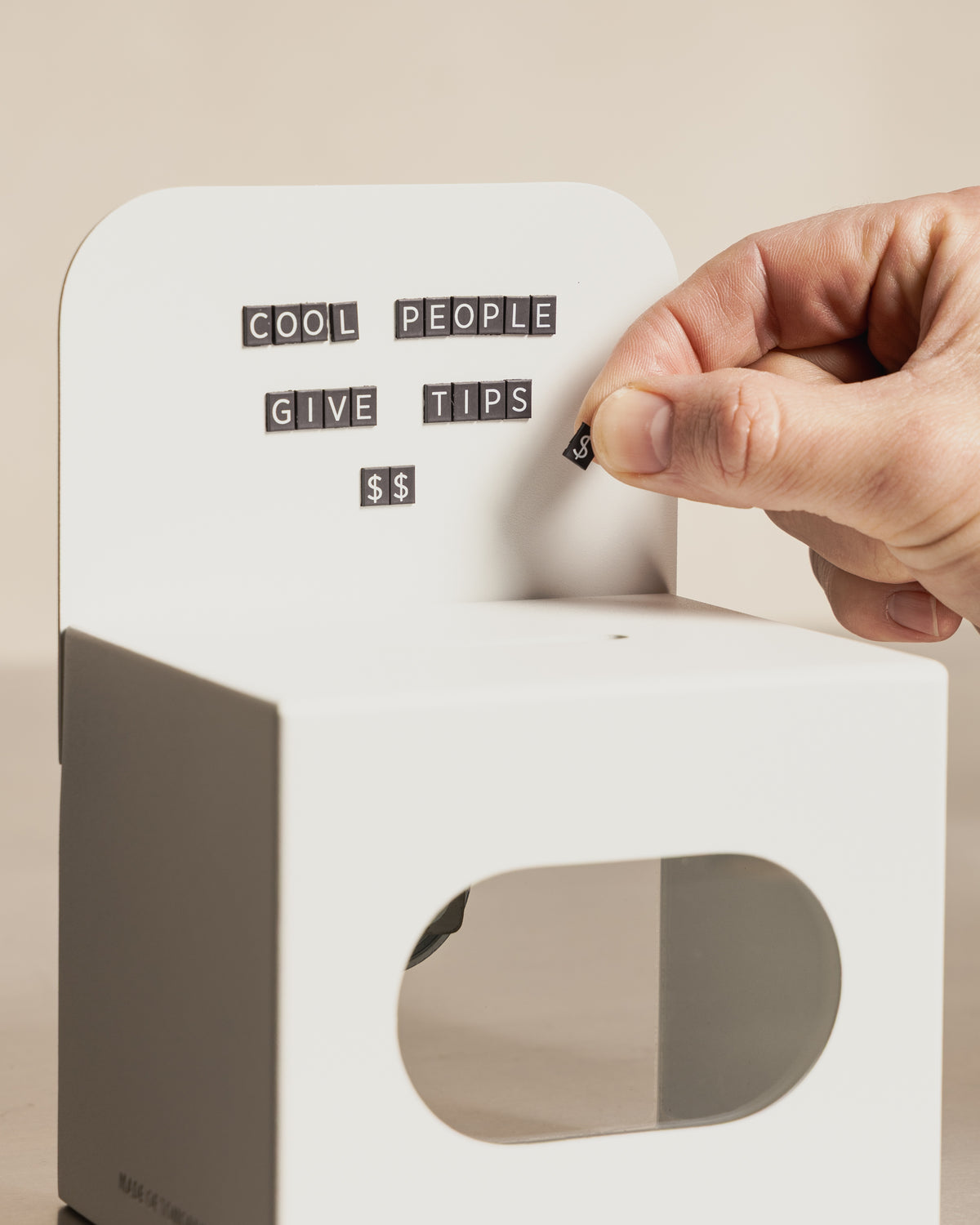 Hand arranging MOT magnetic letters on the white FOLD Tip Box header