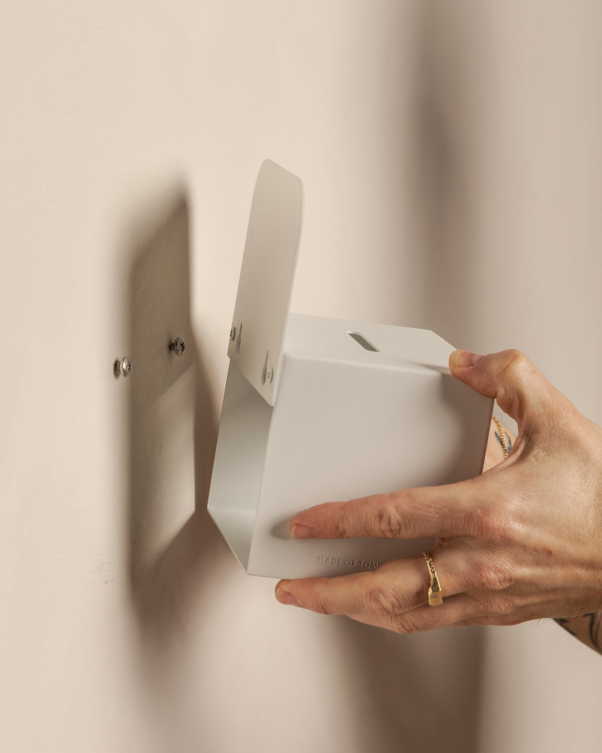 Mounting the white FOLD Tip Box onto wall screws using its keyhole fixings